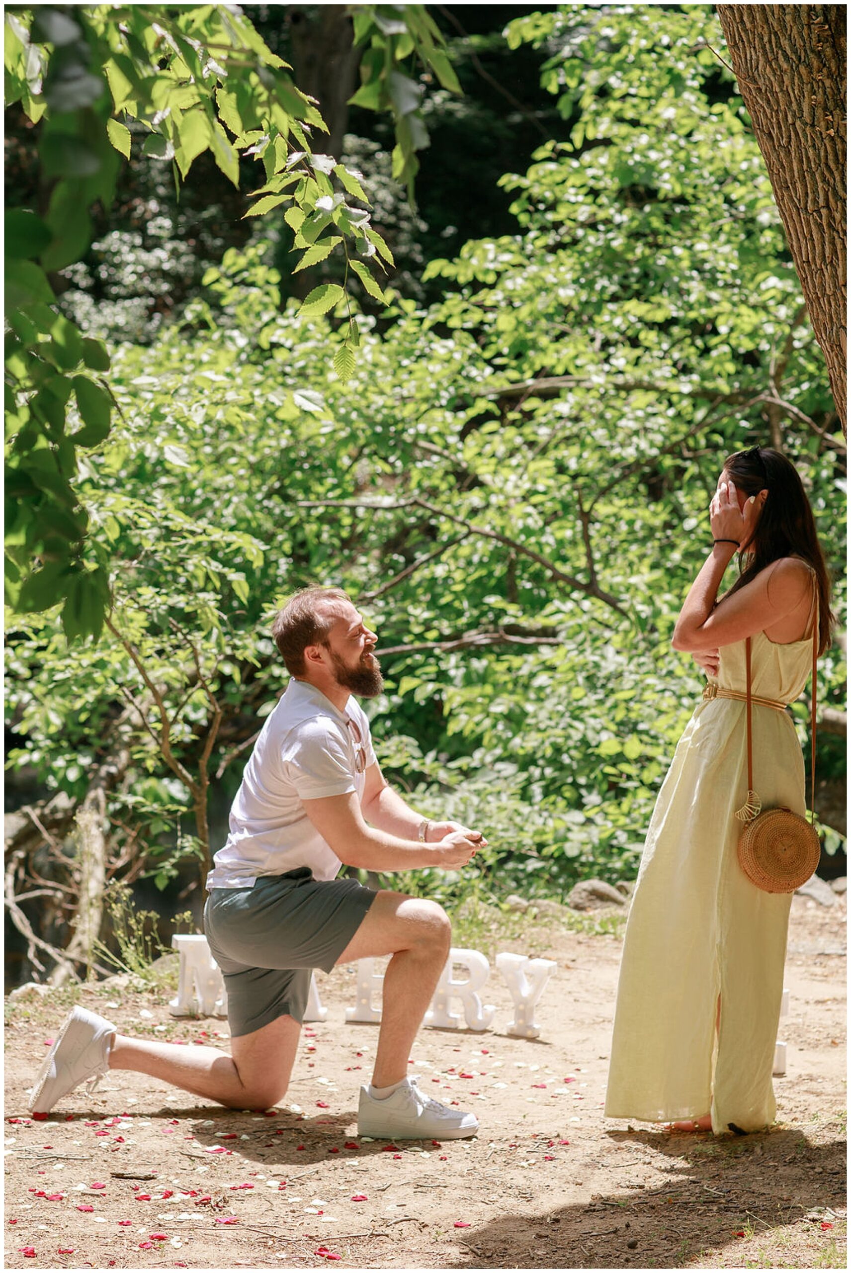 A man gets down on one knee to propose to his girlfriend in a park while she wears a yellow dress dc engagement photographer