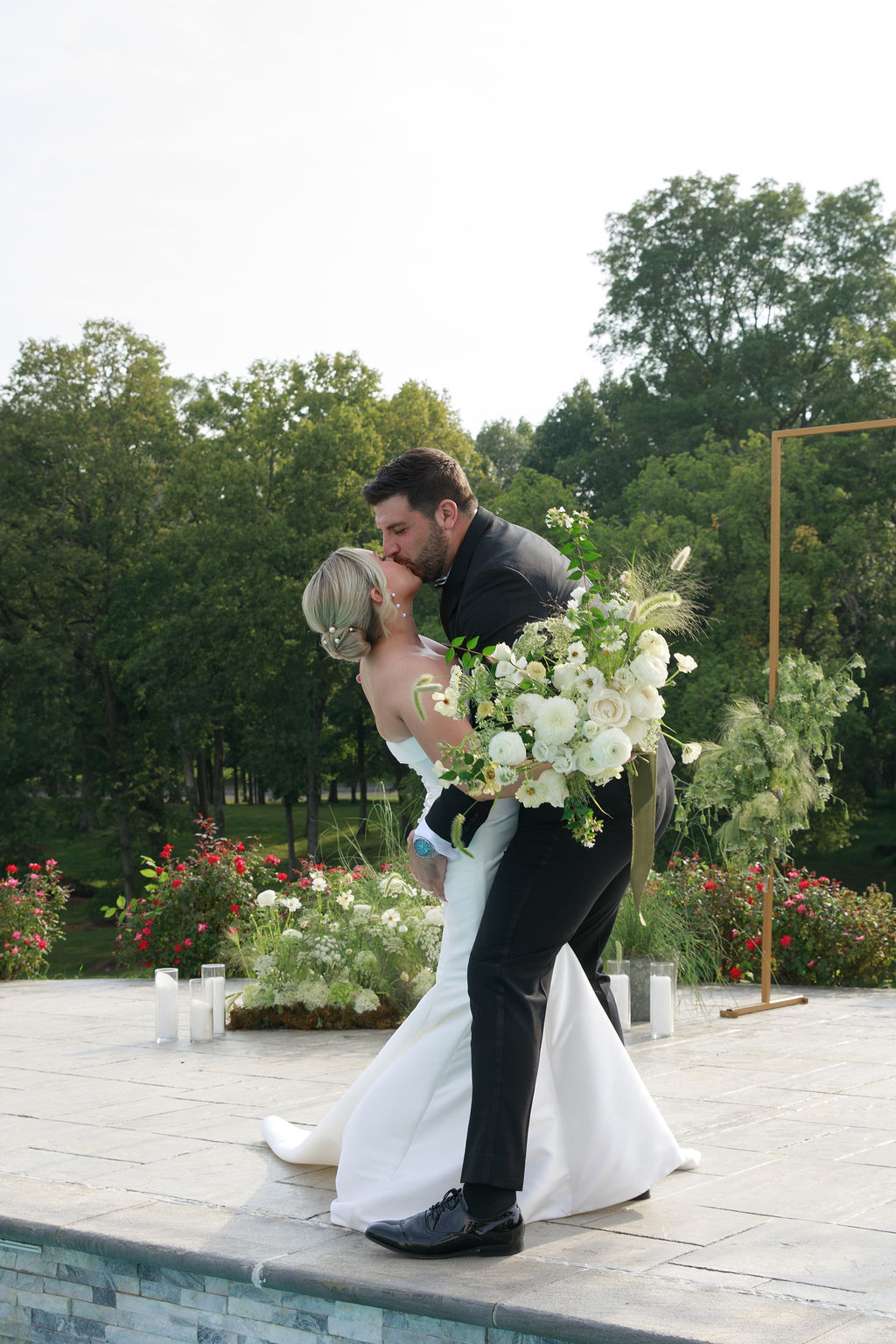 Newlyweds kiss on a stone patio with a dip