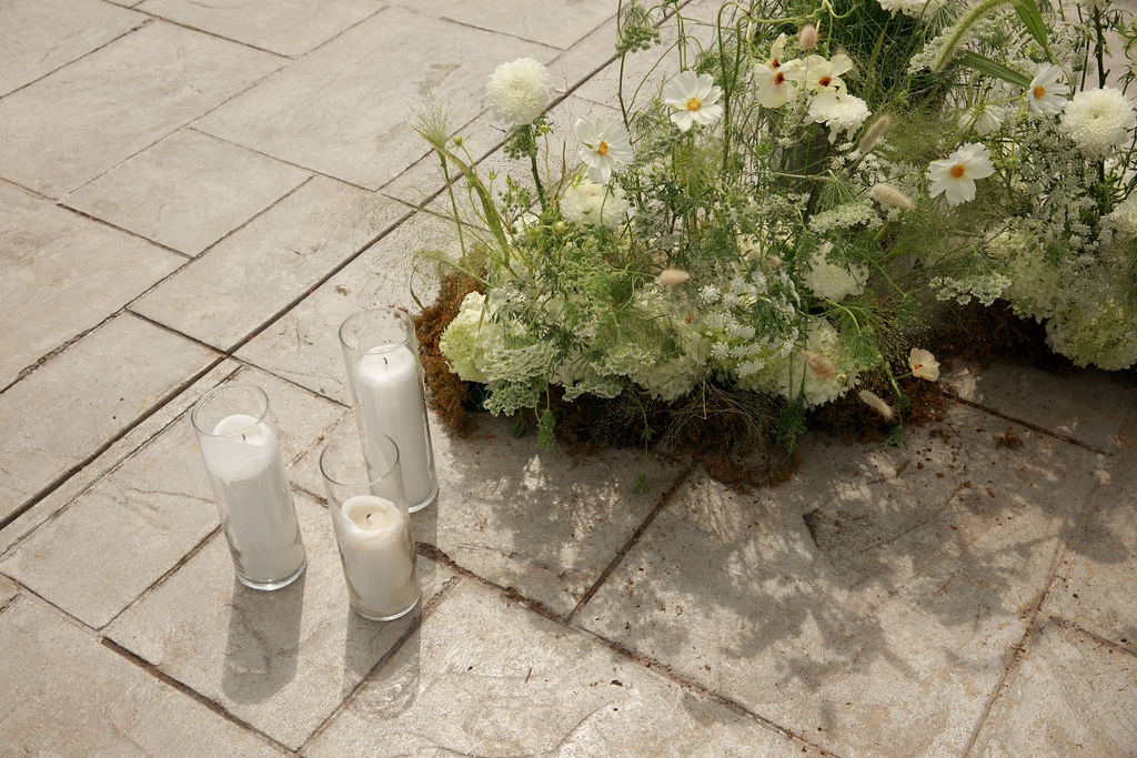 Details of white daisy floral arrangement set for a ceremony on a stone patio with candles washington dc wedding florist