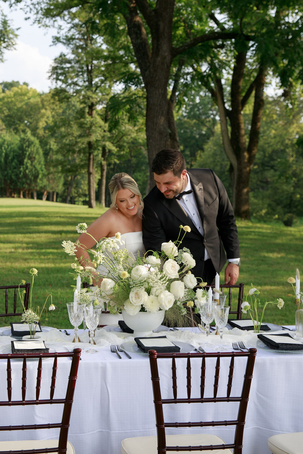 Newlyweds check out their large reception centerpiece at their outside table done by a washington dc wedding florist