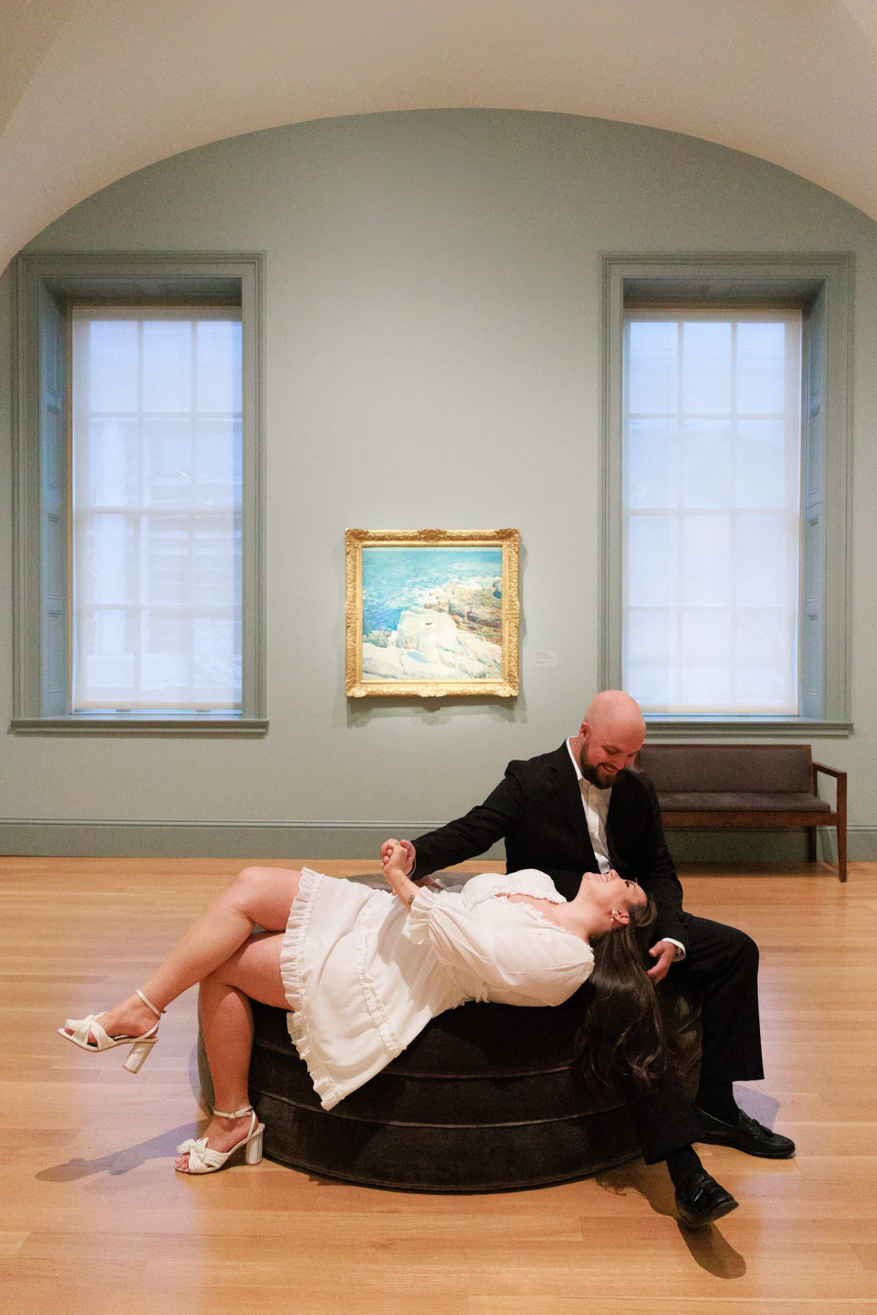 The couple is taking their engagement photos together at an art gallery in Washington DC. This photo features the couple admiring each other.