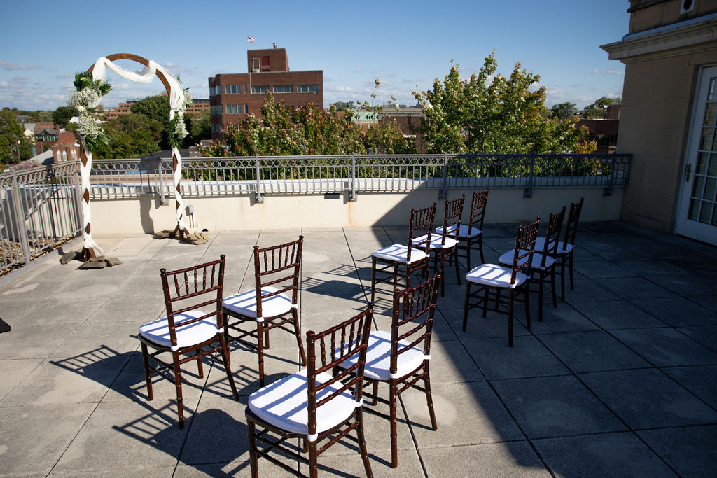 Details of a wedding ceremony set up with wooden chairs and an arbor on a rooftop lorien hotel wedding