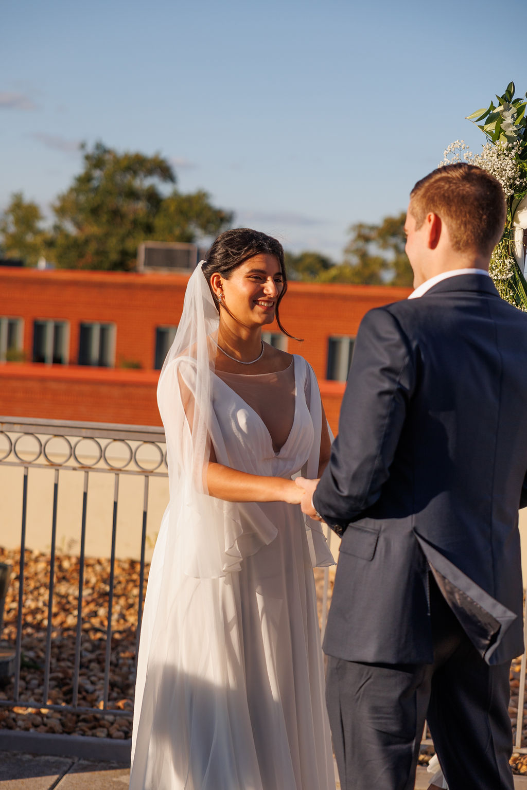 A bride holds her groom's hands during their wedding ceremony