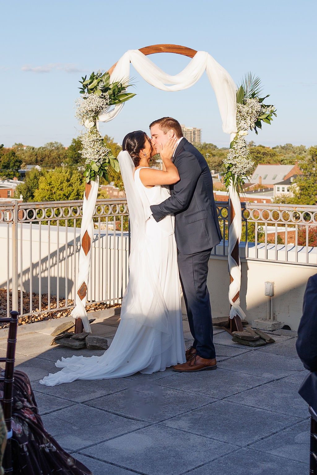 Newlyweds share a big kiss under the arbor to end their rooftop lorien hotel wedding ceremony