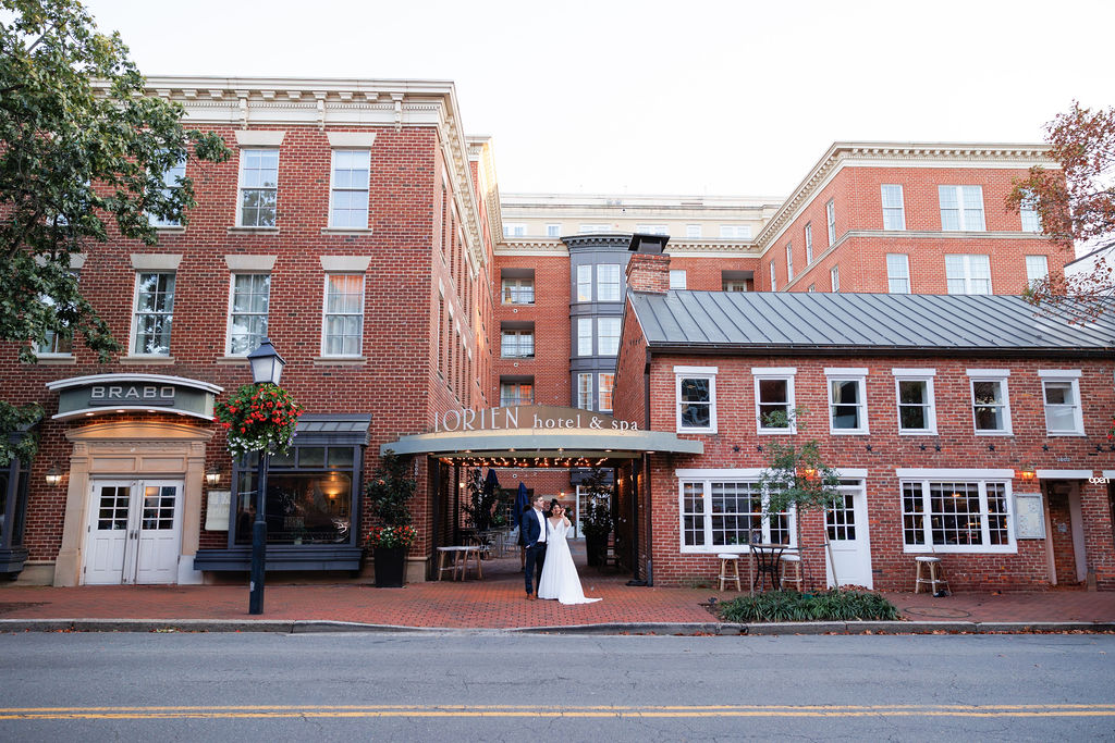 Newlyweds stand together under the brick front facade of the lorien hotel wedding venue