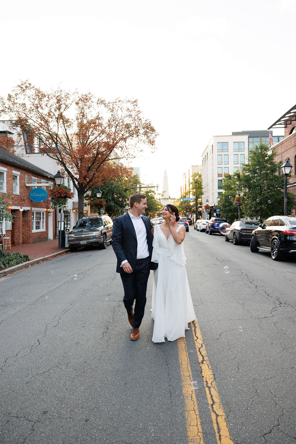 Newlyweds hold hands and walk together down a quiet street