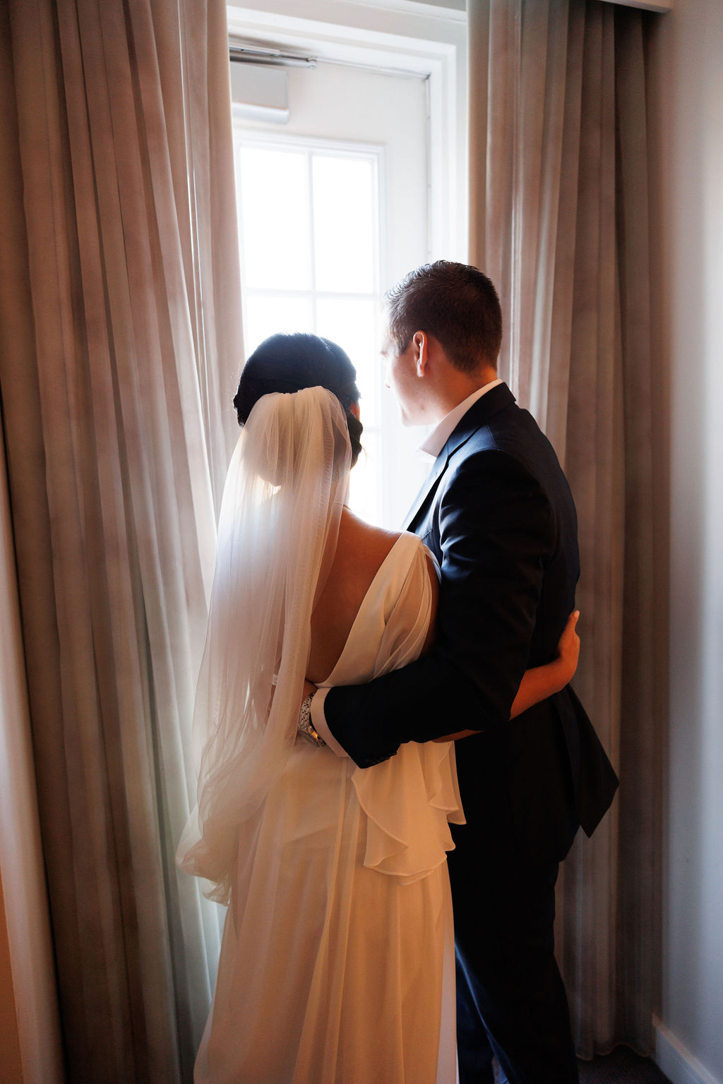 Newlyweds share a quiet moment gazing out a window of a hotel