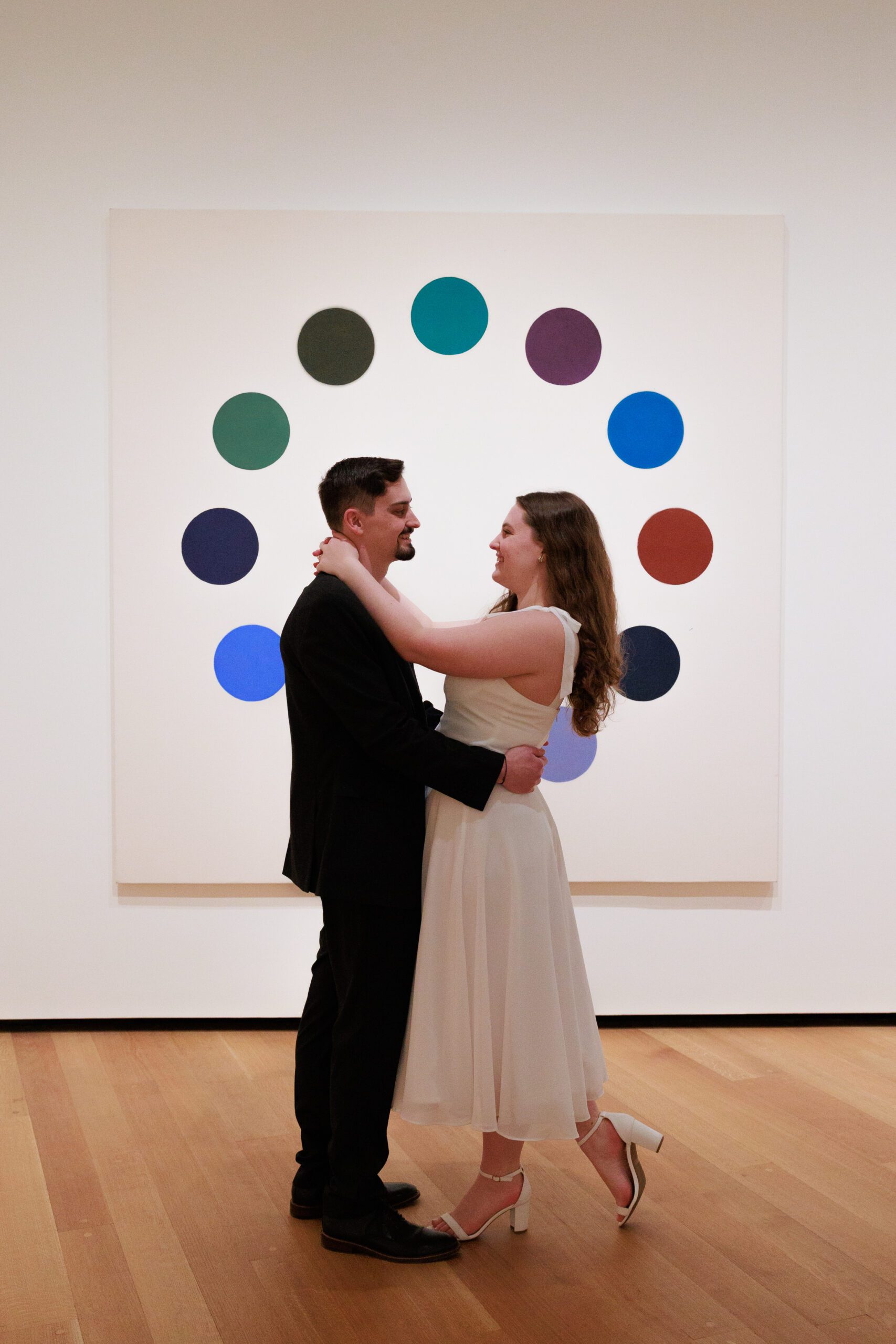 newly engaged couple stand for a photo in front of art with dots on it in the east building of the national gallery of art