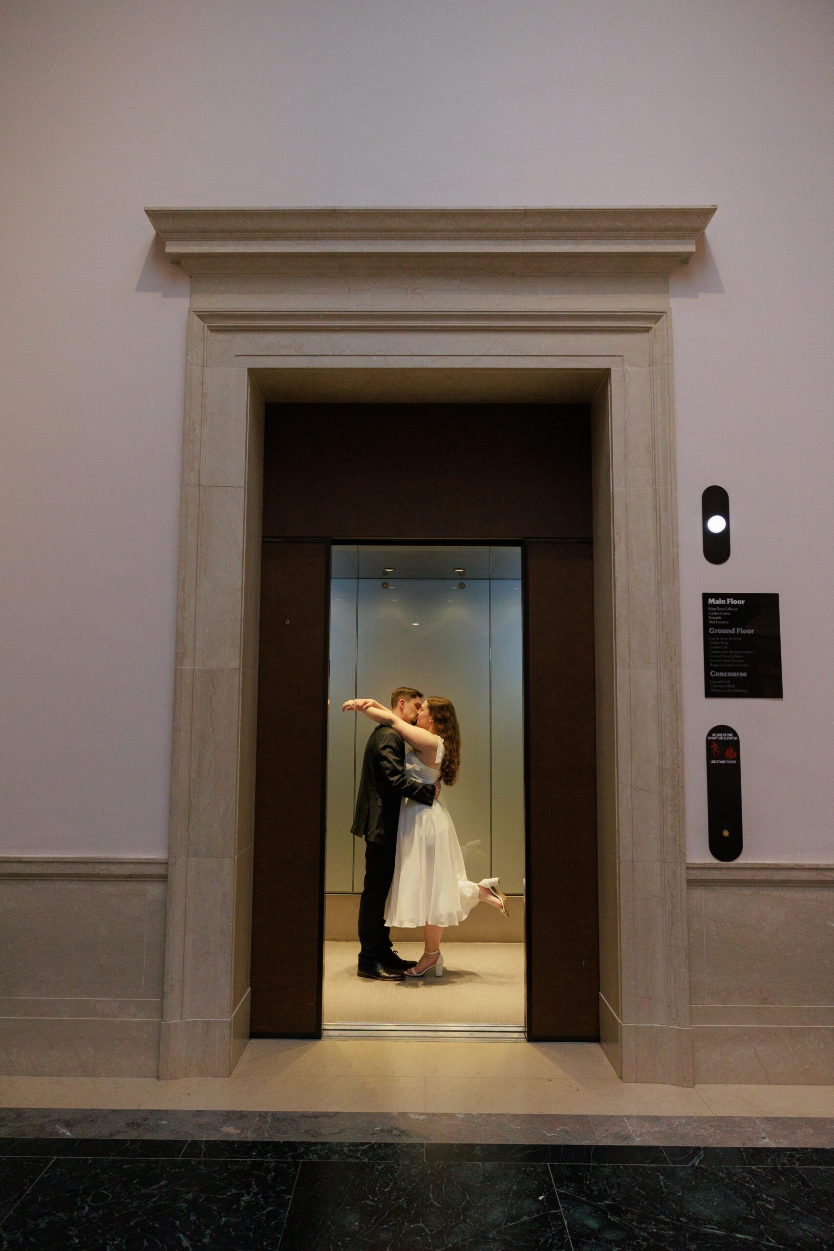 Newly engaged couple shares a kiss in an elevator at the national gallery of art
