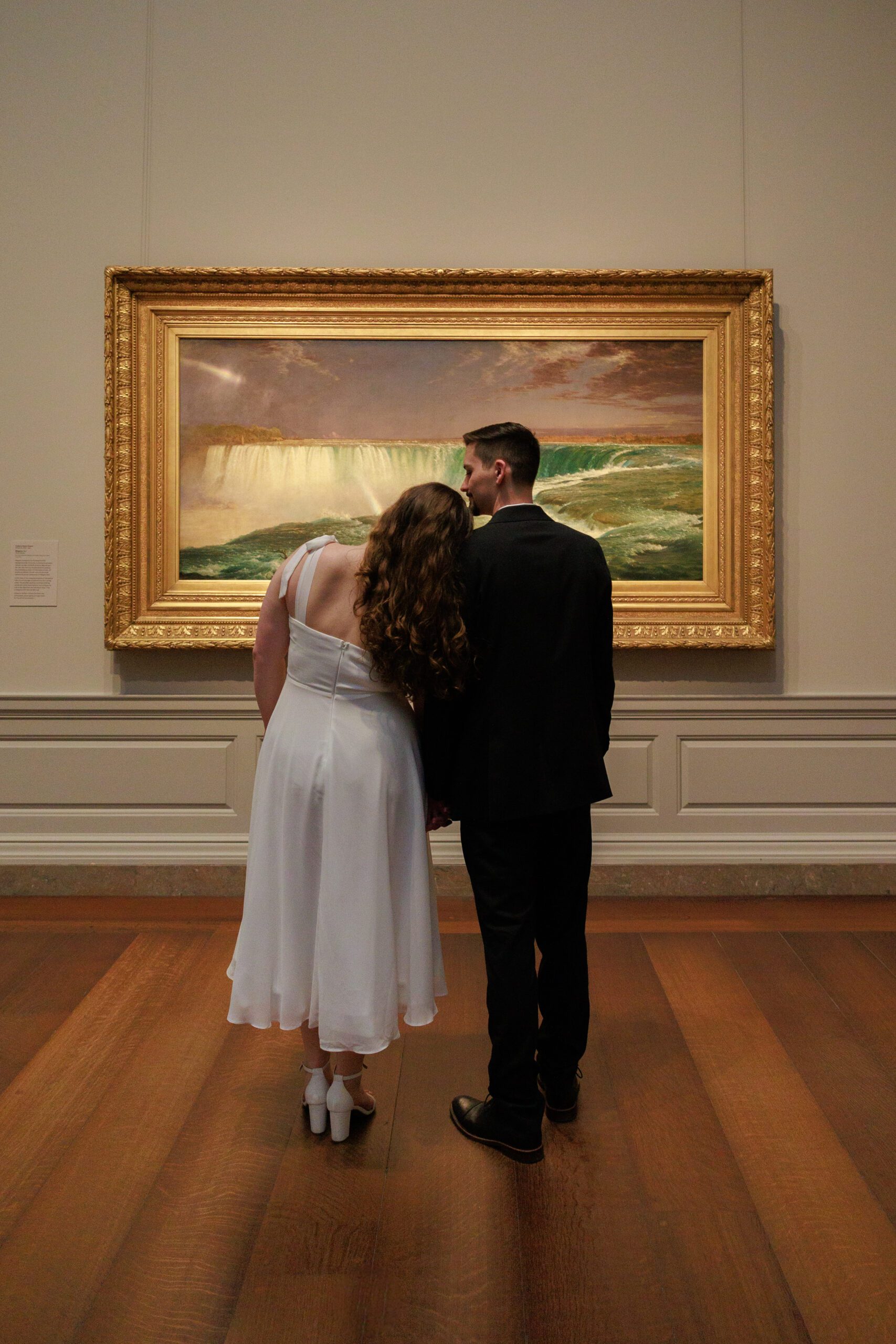 Engaged couple shares a moment in front of a gold frame and waterfall art in washington dc