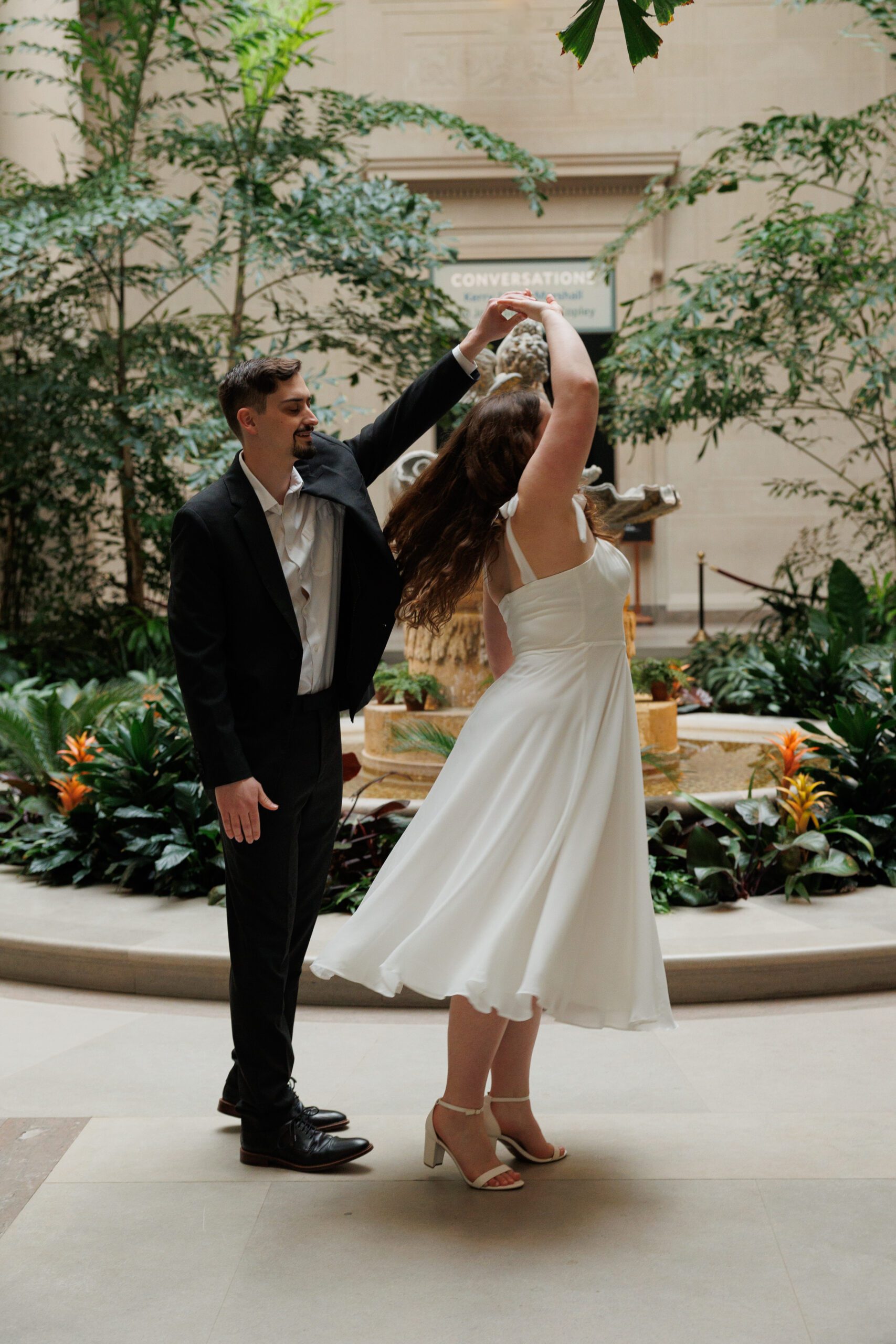 A couple spins and dances for their engagement photos in the west building in the national gallery of art