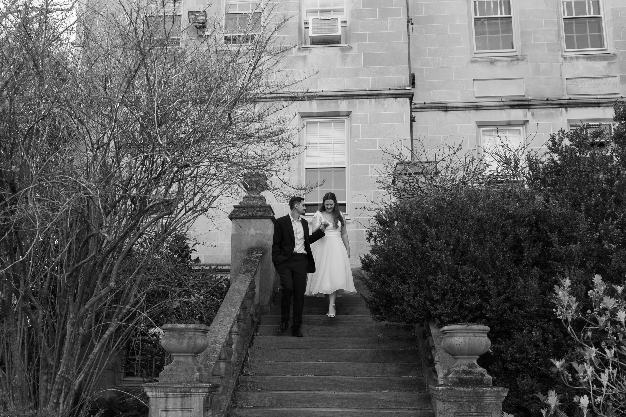 Black and white photo of a couple walking down the stairs together during their engagement session.