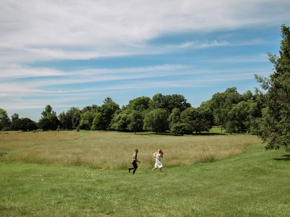 Couple in love runs through a field for romantic engagement photos