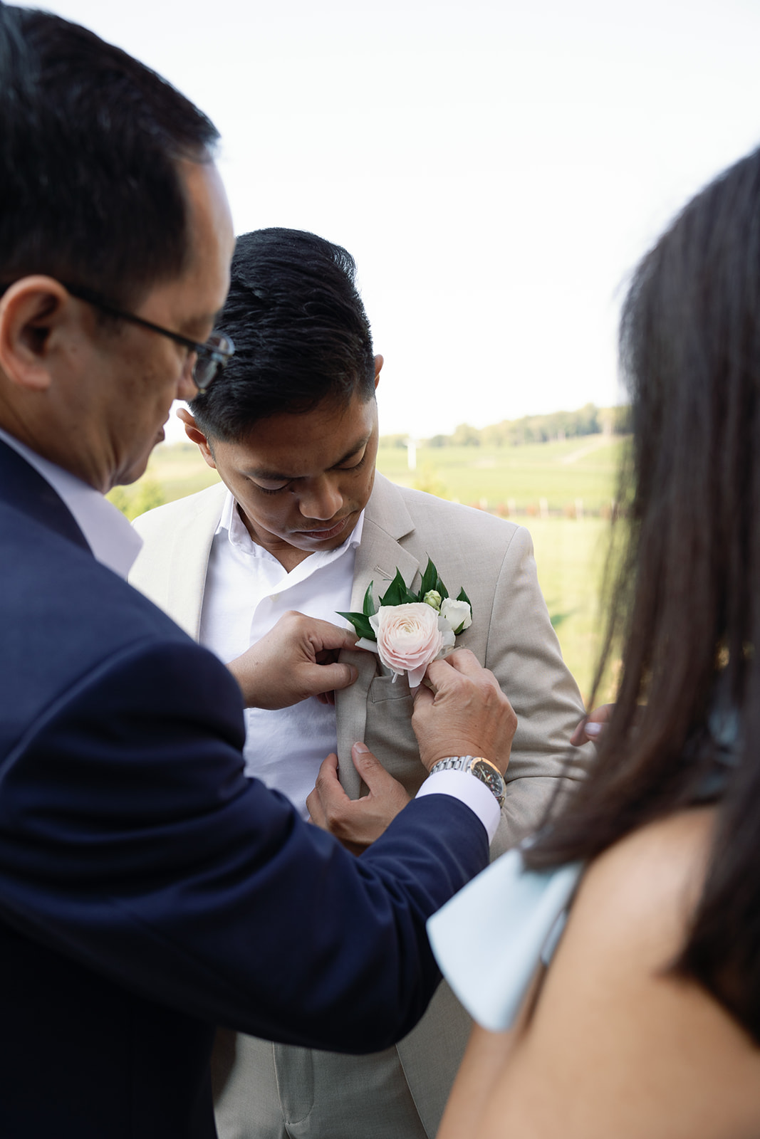 Grooms parents putting on his boutonniere at his wedding.